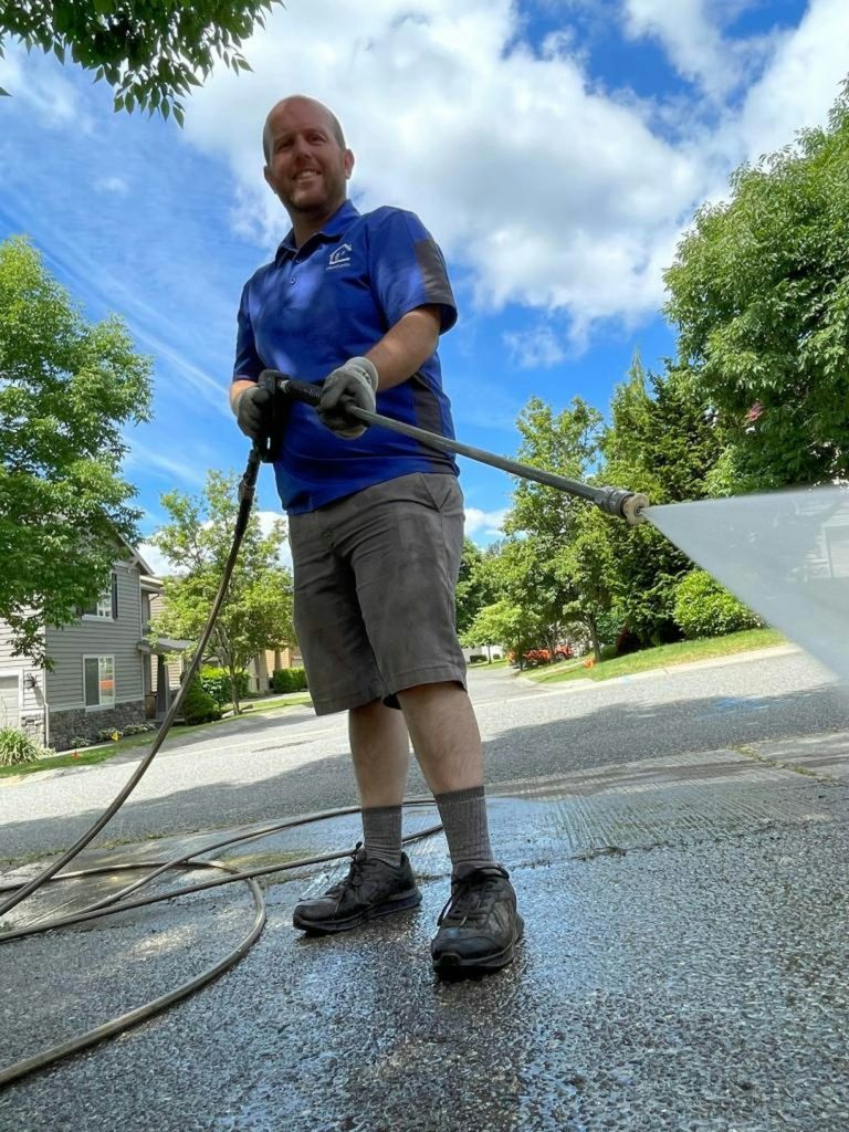 a-man-in-a-blue-shirt-is-washing-a-driveway-kqhsqmllv2i
