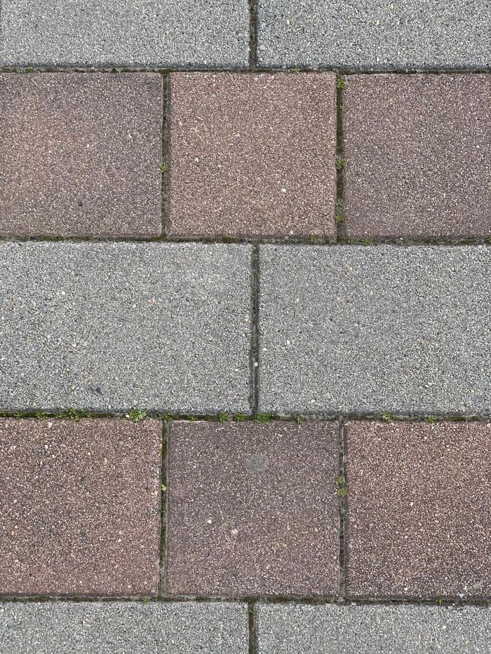 A detailed view of a textured gray and brown brick pavement pattern.