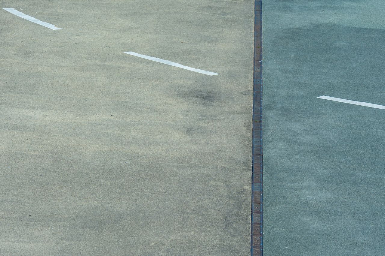 Textured asphalt with white lines in Rotterdam, a minimalist cityscape view.